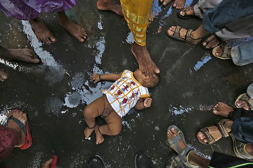 Калькутта, Индия. Садху касается младенца ногой, благословляя ребенка в ходе религиозного фестиваля Шива Гаджан