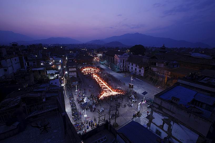 Катманду, Непал. Люди с зажженными свечами выстраиваются в фигуру, напоминающую девятиэтажную башню Басантампур, в годовщину землетрясения, в результате которого год назад были разрушены многие достопримечательности страны