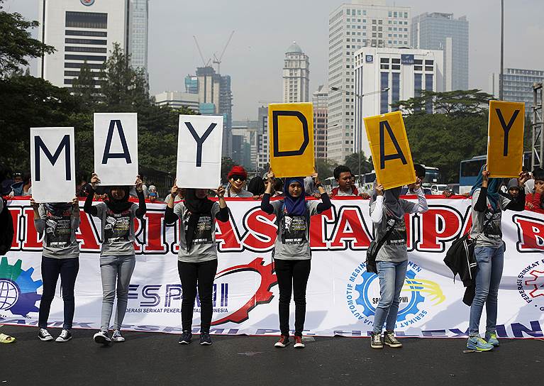 Люди держат плакаты во время первомайского митинга в Джакарте, Индонезия
