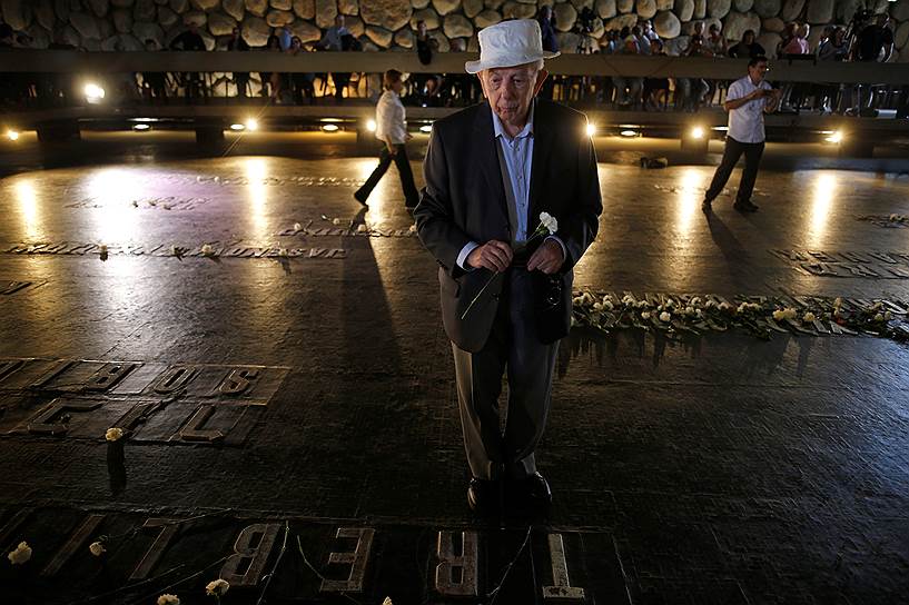 Один из переживших Холокост возлагает цветы во время траурной церемонии в мемориальном комплексе Яд ва-Шем в Иерусалиме 