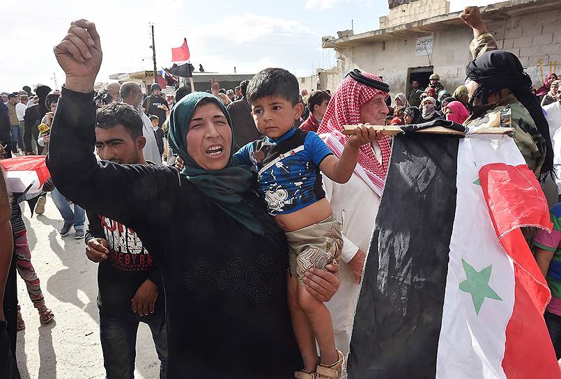 Женщина с детьми и флагом Сирии перед раздачей гуманитарной помощи от России
