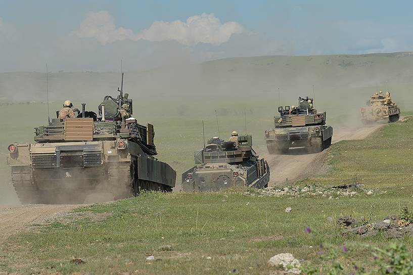 Американские танки M1A2 Abrams и БМП M2 Bradley возвращаются на базу после церемонии открытия