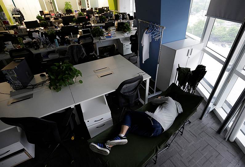 Коу Мэн, продакт-менеджер компании RenRen Credit Management Co., спит на раскладной кровати перед началом рабочего дня
