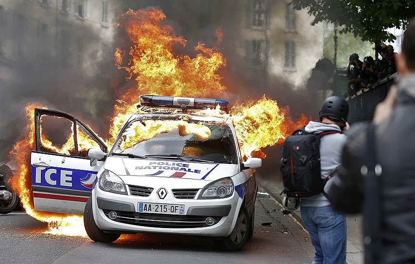 Париж, Франция. Полицейский автомобиль горит во время протестов против насилия со стороны полиции и против реформы трудового законодательства