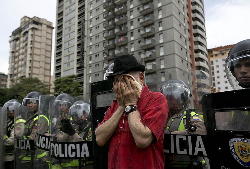 Каракас, Венесуэла. Мужчина, участвующий в акции протеста против президента страны Николаса Мадуро, вытирает лицо после применения полицией слезоточивого газа для разгона демонстрантов