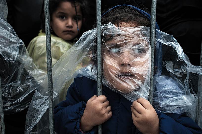 Матич Зорман, Словения. Ребенок-беженец, укрытый плащом от дождя, стоит в очереди на регистрацию в лагере беженцев Прешево в Сербии