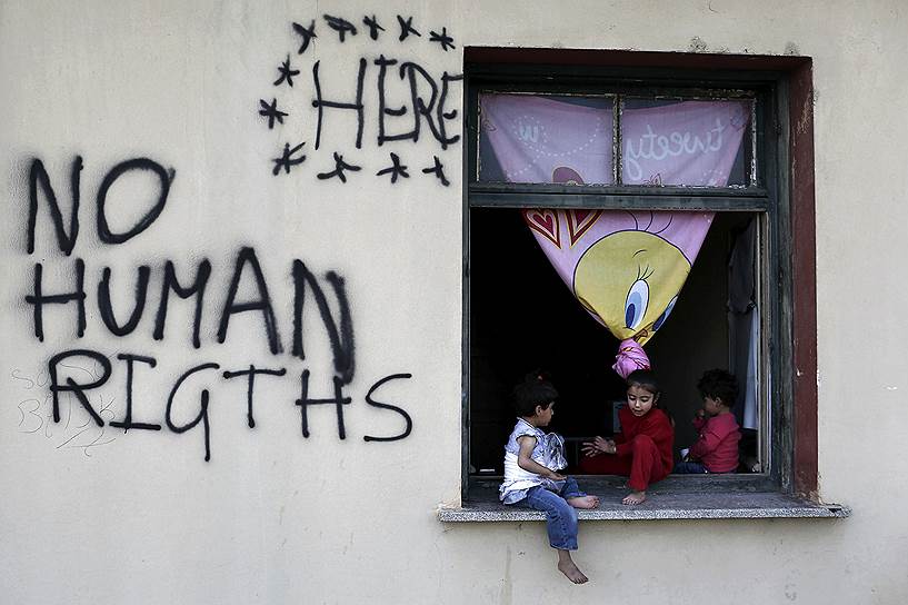 Идомени, Греция. Дети беженцев в окне приюта для мигрантов