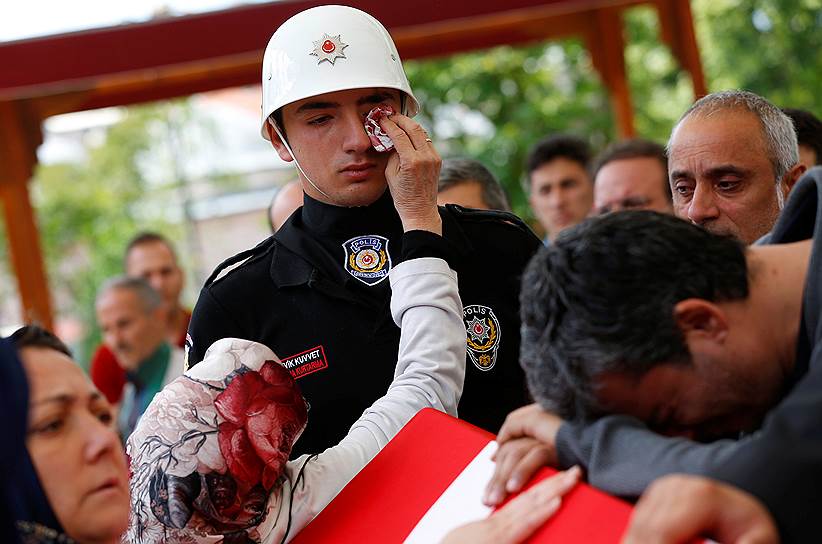Стамбул, Турция. Женщина вытирает слезы члену почетного караула во время похорон офицера полиции, убитого во время нападения  на полицейский автобус у мечети Фатих