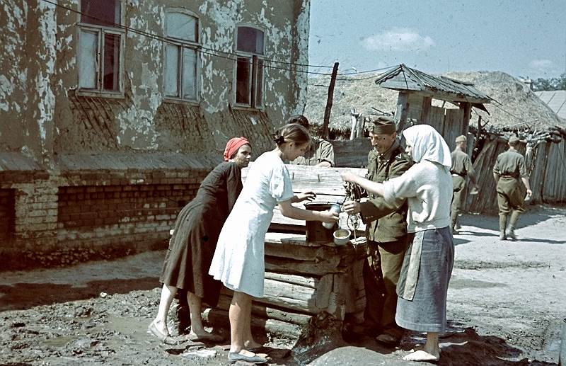 Венгерский солдат с женщинами оккупированного населенного пункта набирает воду из колодца на Восточном фронте