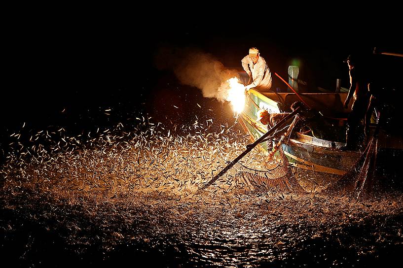 Нью-Тайбэй, Тайвань. Рыбаки на традиционных лодках с помощью огня подманивают рыб