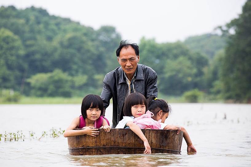 Дучан, Китай. Отец толкает бадью со своими детьми, возвращающимися из школы во время наводнения