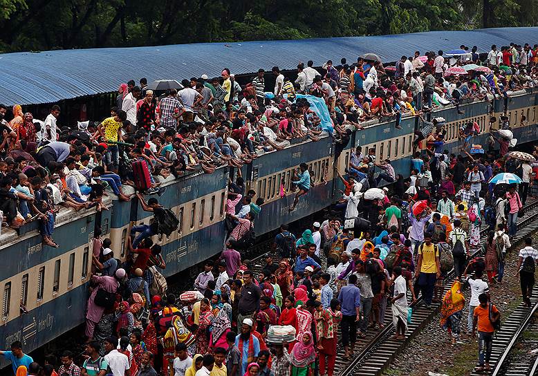 Дакка, Бангладеш. Люди забираются в переполненный поезд, чтобы поехать на празднование Ураза-байрам, отмечаемого в честь окончания поста в месяц Рамадан