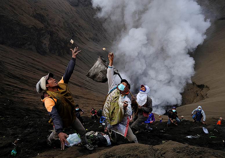 Проболинго, Индонезия. Жители деревни, стоя на склонах вулкана Бромо, ловят деньги, которые паломники бросают в кратер в виде пожертвований для лучшего урожая  