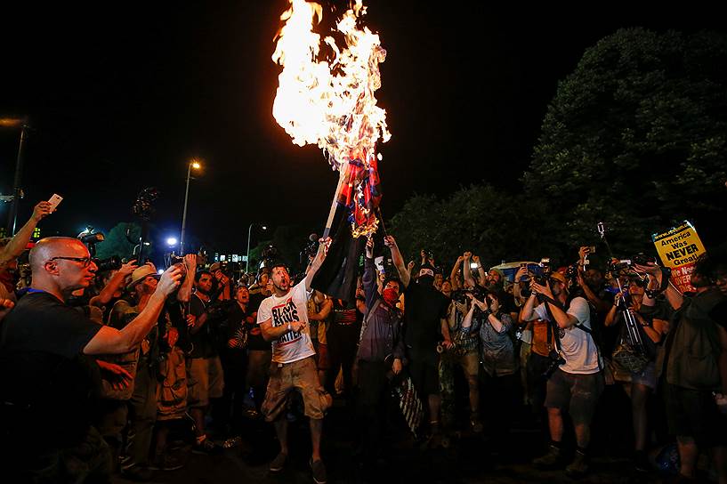 Филадельфия, США. Протестующие сжигают видоизмененный американский флаг у здания, в котором проходил съезд Демократической партии