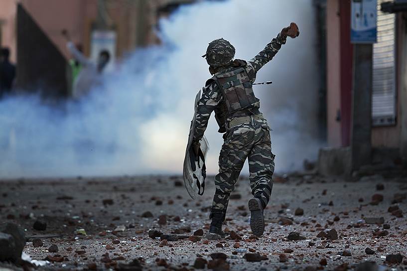 Сринагар, Индия. Индийский солдат бросает камни в сторону протестующих во время подавления акций протестов в Кашмире 