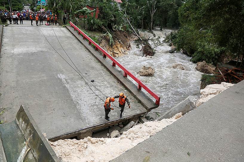 Мелкор-Де-Менко, Гватемала. Члены гватемальской комиссии по чрезвычайным ситуациям (CONRED) стоят на мосту, который разрушился после сильных дождей, вызванных  ураганом Эрл