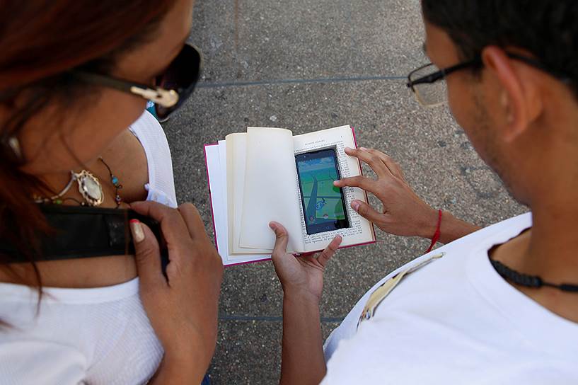 Каракас, Венесуэла. Мать и Сын играют в Pokemon Go, маскируя телефон от кражи 