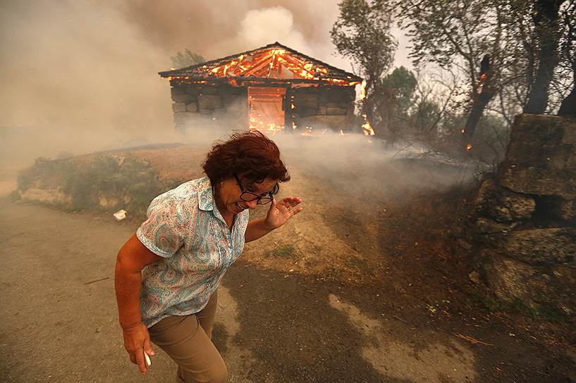 Сан-Педру-ду-Сул, Португалия. Женщина убегает от горящего дома. С 1 августа лесные пожары в Португалии выжгли уже 100 га земли