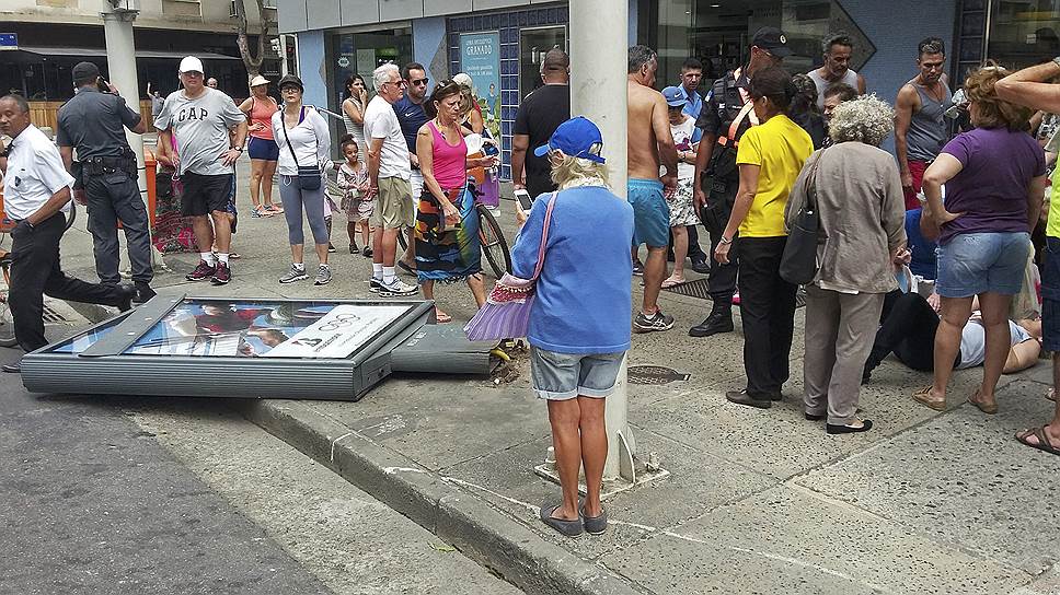 Рекламные конструкции не выдерживают порывистые ветры, которые дуют в Рио-де-Жанейро с начала августа&lt;br>На фото: прохожие помогают женщине, на которую упал рекламный щит