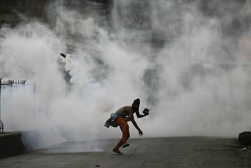 Сринагар, Индия. Протестующий бросает в полицейских шашку со слезоточивым газом. В городе 45-й день продолжаются протесты против убийства активистов в Кашмире