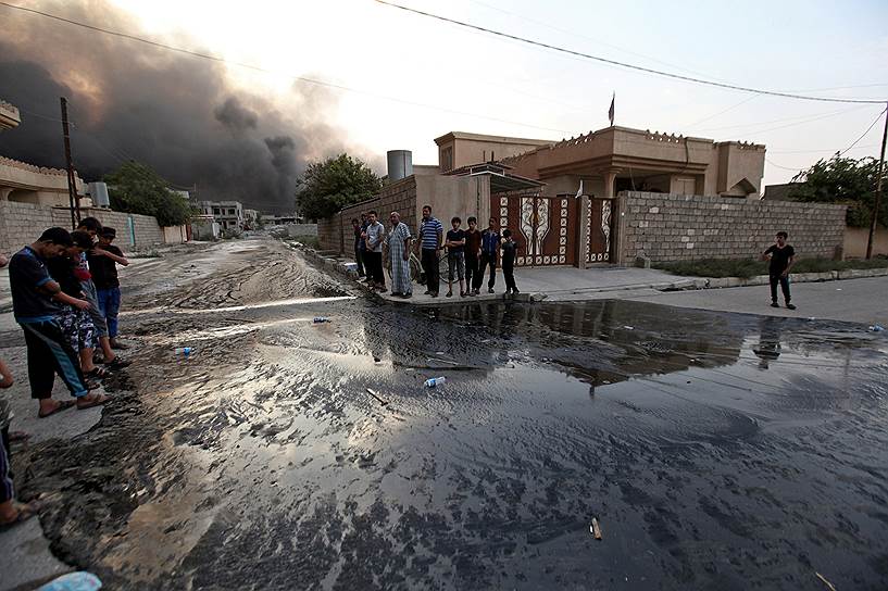 Каяра, Ирак. Жители наблюдают, как горит нефть. Боевики «Исламского государства» (запрещено в России) подожгли нефтехранилище в городе