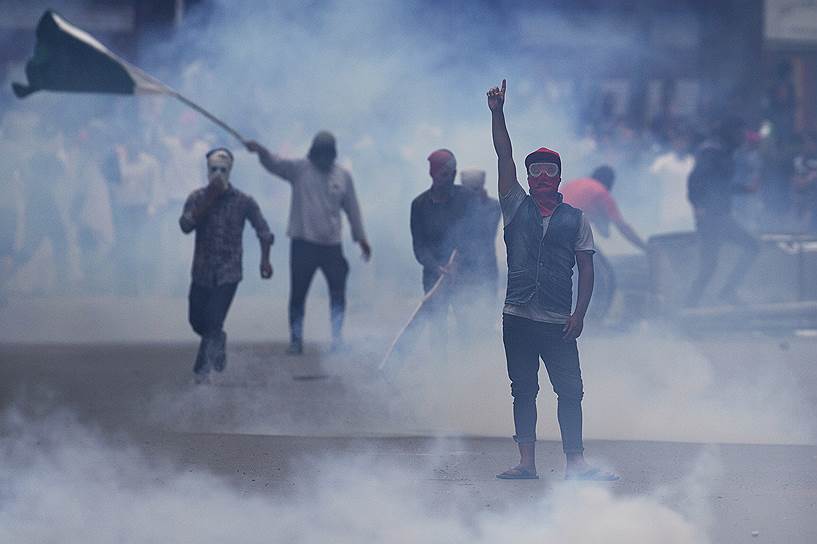 Срингра, Индия. Протестующий в маске выкрикивает лозунги о свободе, пока полиция распыляет слезоточивый газ