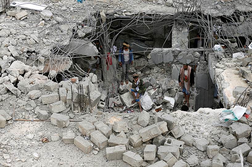 Амран, Йемен. Мужчины ходят среди руин здания, уничтоженного авиаударом Саудовской Аравии  