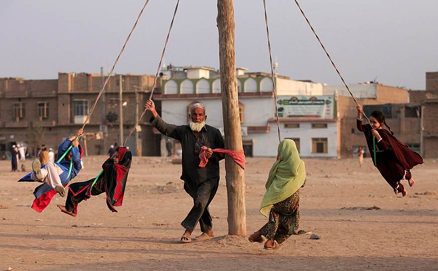 Пешавар, Пакистан. Мужчина катает детей на самодельной карусели