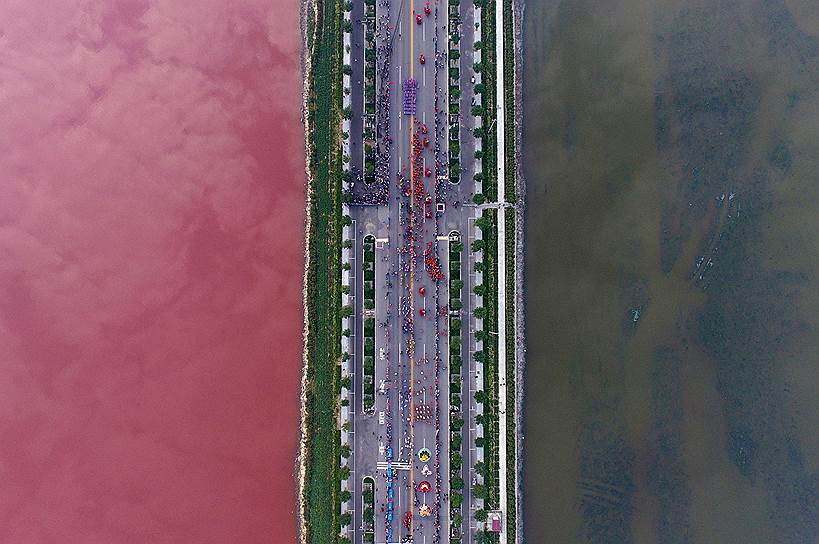 Юньчэн, Китай. Две части соленого озера, разделенного автодорогой, поменяли цвет из за водорослей