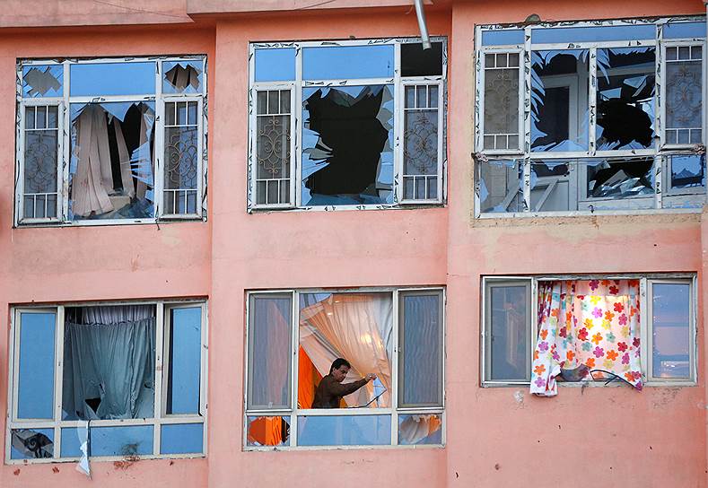 Кабул, Афганистан. Мужчина выбрасывает осколки разбитого окна из своего дома, пострадавшего в результате теракта 