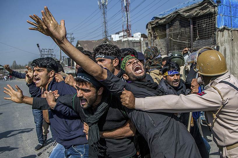 Срингар, Индия. Полицейский пытается остановить мусульманскую похоронную процессию во время комендантского часа