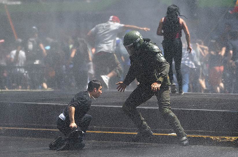 Сантьяго, Чили. Полиция пытается задержать демонстранта во время акции протеста индейцев мапуче против празднования дня Христофора Колумба