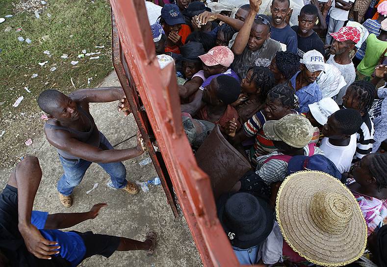 Маниш, Гаити. Охранники закрывают ворота перед людьми, которые пытаются прорваться на территорию, где раздается гуманитарная помощь 
