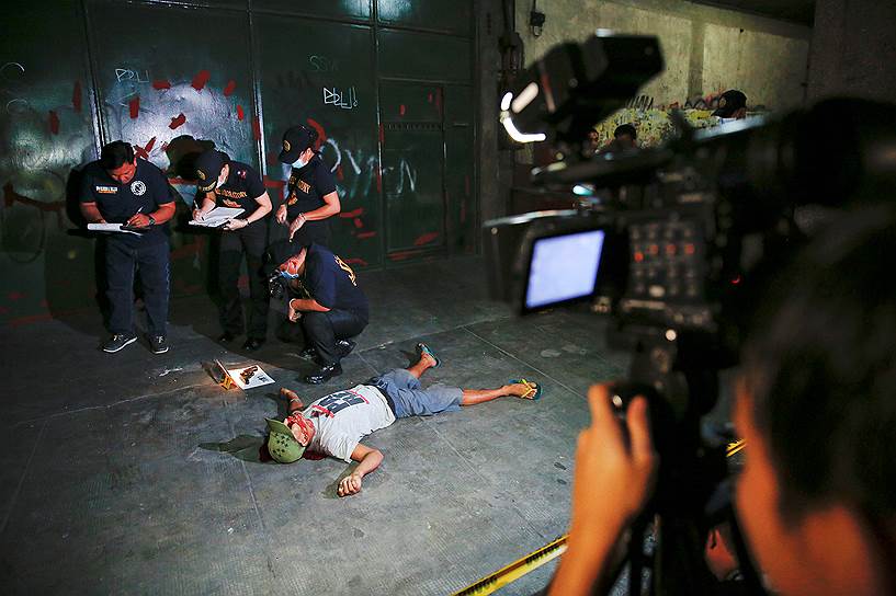Манила, Филиппины. Полицейские во время осмотра убитого в нарковойне мужчины 