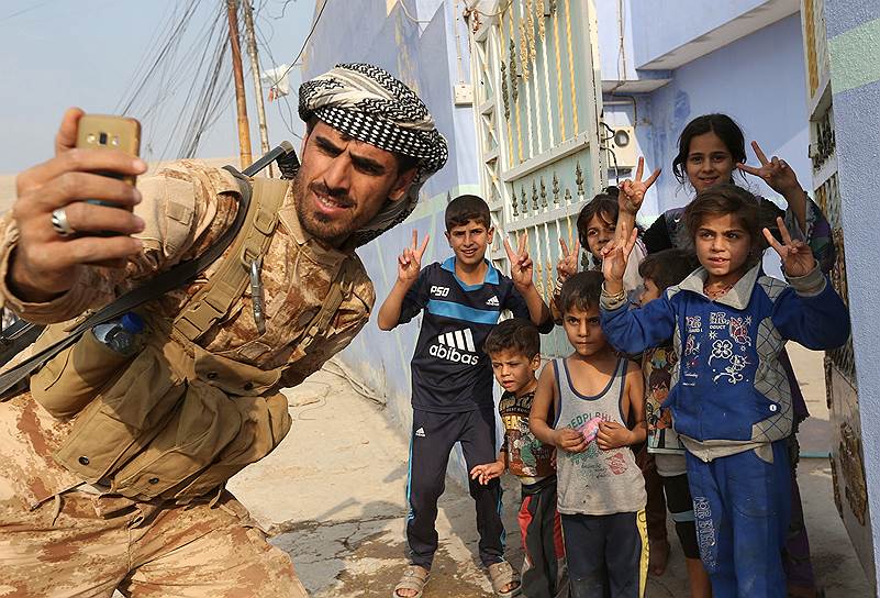 Мосул, Ирак. Боец курдской группировки «Пешмерга» делает селфи с детьми после освобождения одной из деревень от боевиков «Исламского государства»