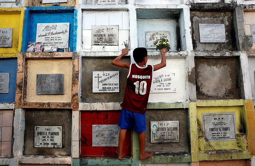 Манила, Филиппины. Ребенок расставляет букеты на могилы умерших в ходе нарковойны 