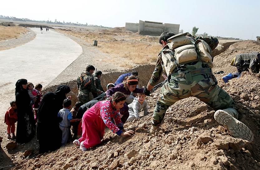 Абу Джарбоа, Ирак. Курдские повстанцы помогают женщинам и детям, покидающим территории, контролируемые боевиками ИГ, перебраться через насыпь