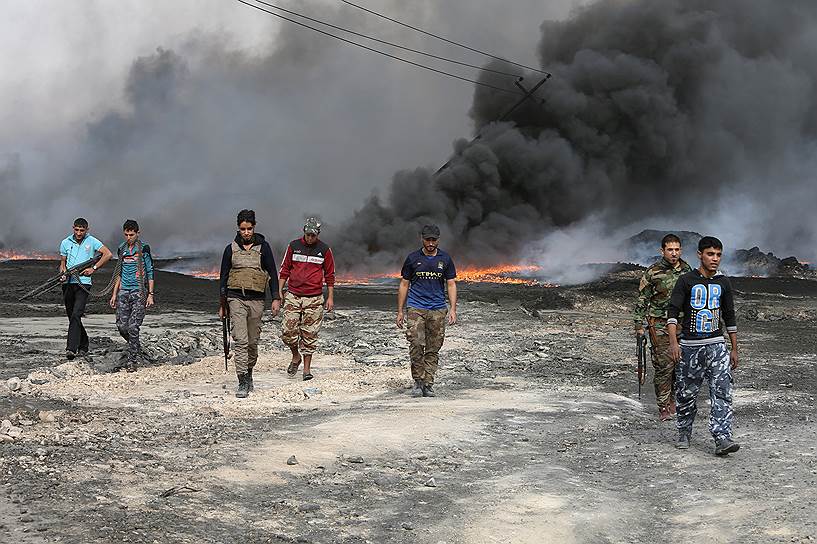 Кайяра, Ирак. Повстанцы на фоне горящей нефтяной скважины, которую подожгли террористы «Исламского государства» перед тем, как покинуть этот район