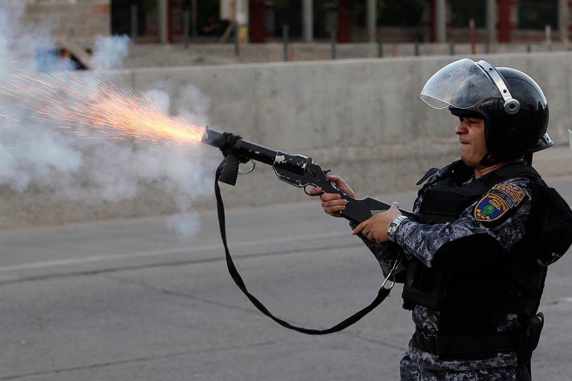 Тегусигальпа, Гондурас. Сотрудник полиции, выпускающий газовую гранату во время акции протеста против переизбрания президента Хуана Орландо Эрнандеса