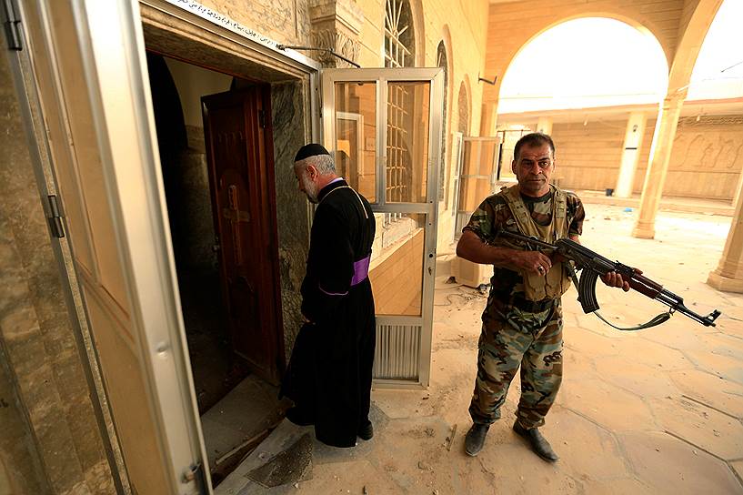 Башика. Священник и военный на входе в отбитый у террористов «Исламского государства» храм