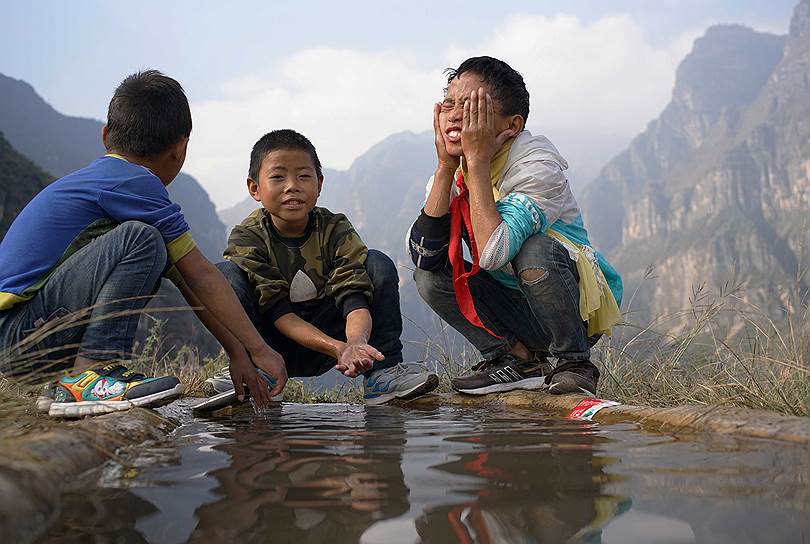 Ляншань-Ийский автономный округ, Китай. Школьники сделали остановку на недавно обустроенной дороге в горную деревню