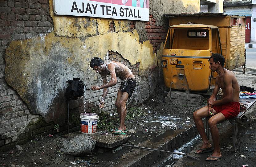 Джамму, Индия. Местные жители моются, набирая воду из уличного крана на рынке