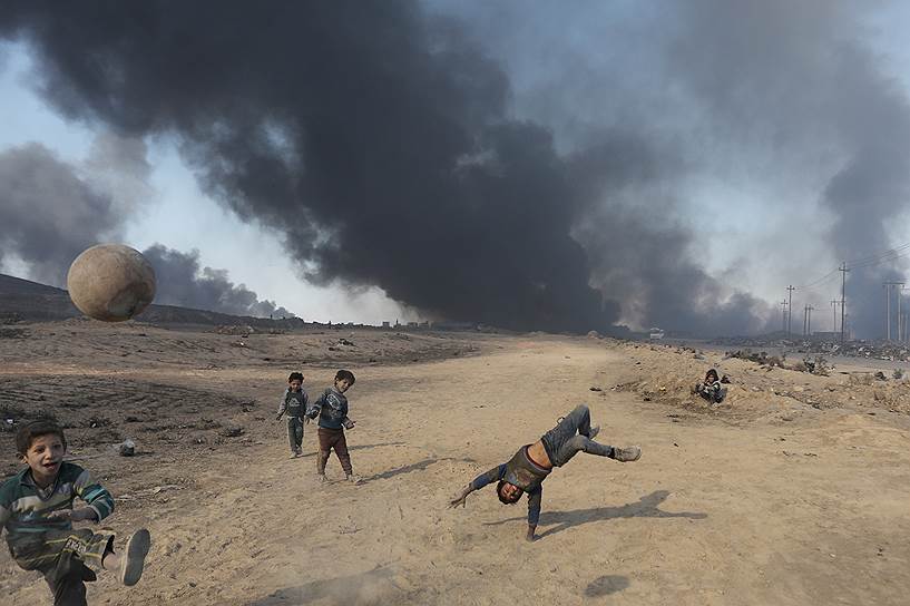Кайяра, Ирак. Дети играют на фоне горящих нефтяных месторождений, подожженных боевиками «Исламского государства»
