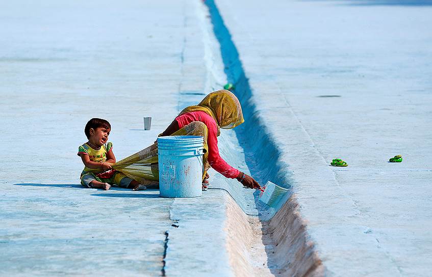 Дели, Индия. Женщина красит водосток