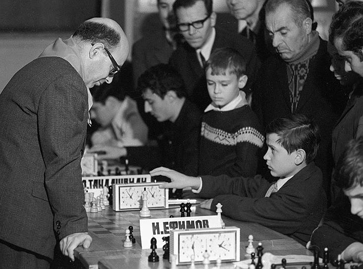 Давид Бронштейн стал претендентом на звание чемпиона мира в 27 лет. В 1951 году он встречался с Михаилом Ботвинником, который впервые отстаивал свой титул. Матч завершился вничью (12:12), и чемпион остался на троне. Тем не менее влияние Бронштейна до сих пор прослеживается в игре многих шахматистов. Он стоял у истоков соревнований по быстрым шахматам, а также придумал систему, при которой гроссмейстеры одновременно играют друг с другом несколько партий&lt;br>На фото: Давид Бронштейн и 12-летний школьник из Тбилиси в Центральном шахматном клубе в Москве