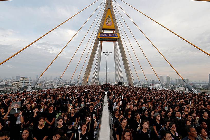 Бангкок, Таиланд. Люди, пришедшие на акцию памяти умершего короля страны Пхумипона Адульядета, собрались на мосту, названном в его честь