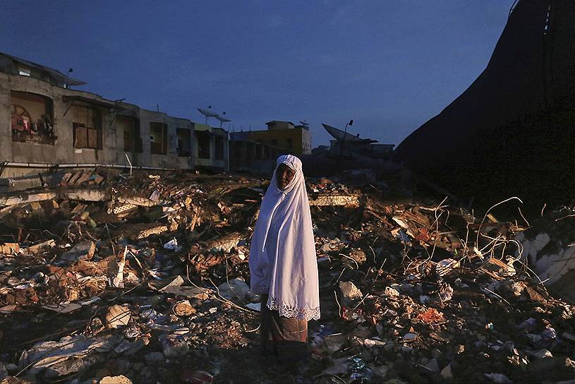 Ачех, Индонезия. Женщина стоит среди в разрушенном землетрясением квартале