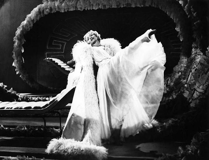 «Мои платья — эфемерные предметы архитектуры, предназначенные для того, чтобы прославлять пропорции женского тела»&lt;br>В 1950-е годы Кристиан Диор создавал костюмы для театральных постановок и кино. В частности, он создавал образы для балетов Ролана Пети. В платьях от Диора появлялись героини фильмов Альфреда Хичкока. В 1955 году кутюрье был номинирован на «Оскар» за лучший дизайн костюмов для картины «Вокзал Термини» режиссера Витторио Де Сики&lt;br>На фото: Марлен Дитрих в платье от Кристиана Диора во время выступления