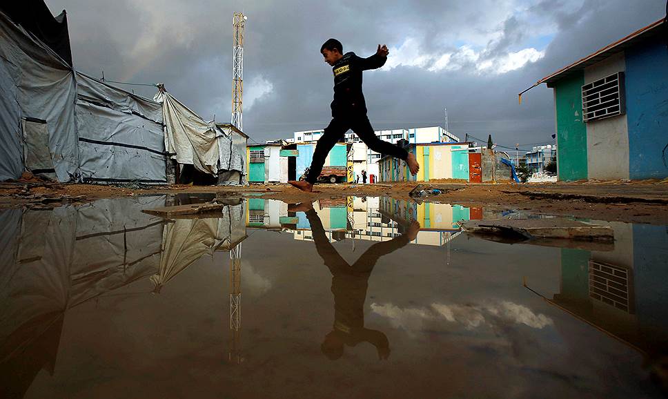 Бейт-Ханун, Сектор Газа. Мальчик перепрыгивает через лужу в лагере для беженцев