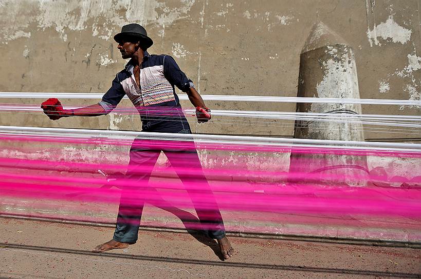 Ахмадабад, Индия. Рабочий красит веревки для воздушных змеев